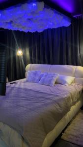 a bedroom with a large white bed with purple lighting at Ecrin secret in Aubagne
