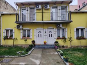 ein gelbes Haus mit weißen Türen und einem Balkon in der Unterkunft Odličan smeštaj blizu centra in Novi Sad