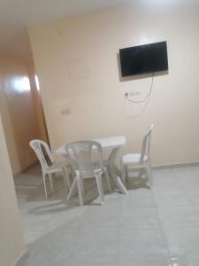 a white table with chairs and a tv on a wall at شقة مريحة بجانب مطار المسيرة اكادير in Ikhorbane