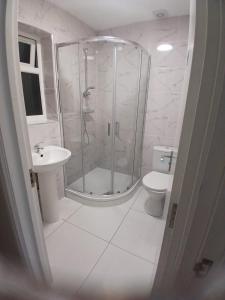 a bathroom with a shower and a toilet and a sink at The Stadium Rooms Elegant and Comfy Stay in London