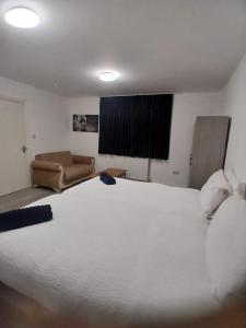 a bedroom with a large white bed and a couch at The Stadium Rooms Elegant and Comfy Stay in London