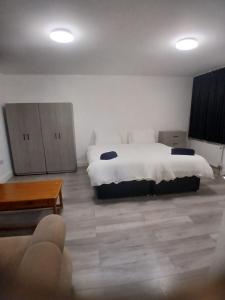 a bedroom with two beds and a table and a couch at The Stadium Rooms Elegant and Comfy Stay in London