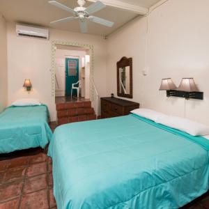 ein Schlafzimmer mit zwei Betten und einem Spiegel in der Unterkunft Trade Winds Restaurant & Guest House in Vieques