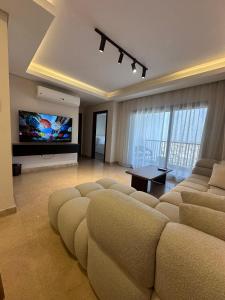 - un salon avec un grand canapé et une télévision à écran plat dans l'établissement شقة فندقيه ابراج zedالشيخ زايد, à Sheikh Zayed