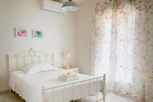 a white bedroom with a white bed and a window at Fairy home Porto Heli in Porto Heli