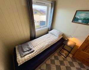 a small bed in a room with a window at Cozy house on Sommarøy in Sommarøy