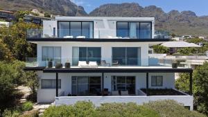 ein weißes Haus mit Bergen im Hintergrund in der Unterkunft Sovn Boutique Hotel in Kapstadt