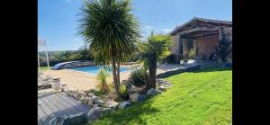 a house with a swimming pool and two palm trees at La Cour de la Forêt in Saint-Mars-de-Coutais