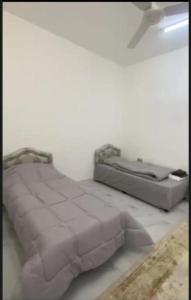 a white bedroom with a bed and a ceiling fan at بيت دار السوداء in Dār Sawdāʼ