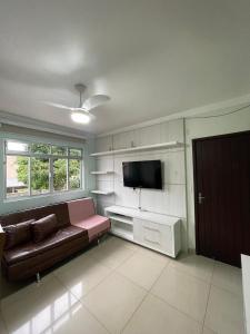 a living room with a couch and a flat screen tv at Residencial Nicole in Florianópolis
