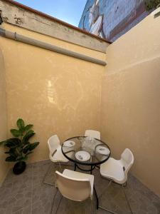 un patio avec une table en verre et des chaises blanches dans l'établissement Superbe maison d artiste avec patio centre ville, à Sète 2 autres photos