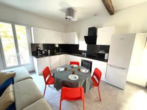 une cuisine avec une table et des chaises rouges dans une pièce dans l'établissement Superbe maison d artiste avec patio centre ville, à Sète