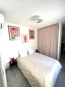 - une chambre avec un lit blanc et quelques photos sur le mur dans l'établissement Superbe maison d artiste avec patio centre ville, à Sète