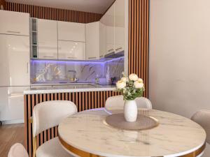 サラエボにあるLuxury apartment 304 - next to Sarajevo City Centerの花瓶に花が飾られたテーブルのあるキッチン