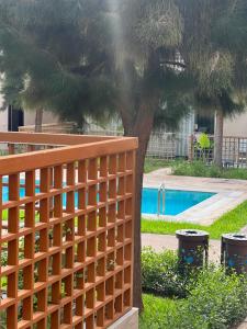 Ein Holzzaun neben einem Baum neben einem Pool in der Unterkunft Luxury 2BR Apartment Taghazout Bay 1 min walk to beach in Tamraght Ouzdar