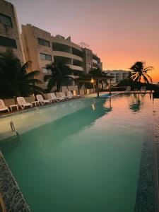 une grande piscine avec des chaises et un bâtiment dans l'établissement Departamento frente al mar con alberca, à Telchac Puerto