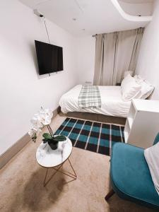 a bedroom with a bed and a table and a couch at Charming Studio in the Heart of Ealing Broadway in Ealing