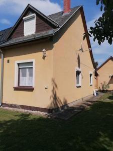 une maison jaune avec une fenêtre et un toit dans l'établissement Haus Sissy, à Balatonkeresztúr 16 autres photos