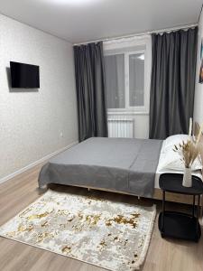 ein Schlafzimmer mit einem Bett, einem Fenster und einem Teppich in der Unterkunft Однокомнатная квартира 463 in Qostanai