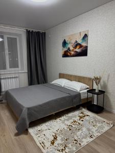ein Schlafzimmer mit einem großen Bett und einem Teppich in der Unterkunft Однокомнатная квартира 463 in Qostanai