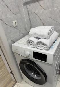eine Waschmaschine mit Handtüchern darauf in einem Badezimmer in der Unterkunft Однокомнатная квартира 463 in Qostanai