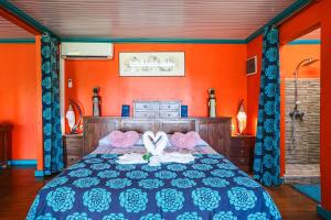 a bedroom with a bed with an orange wall at Villa douillette à Deshaies – Vue sur la mer et la montagne - 96 m² in Deshaies