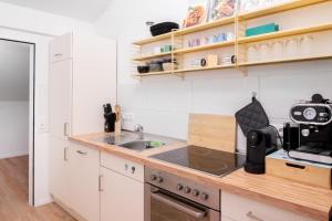 a kitchen with white cabinets and a sink at Design-Apartment Worpswede in Worpswede +3 photos