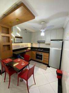 a kitchen with a table and chairs and a refrigerator at Próximo a praia das castanheiras, internet, cooler, cadeiras de praia,roupas de cama e banho in Guarapari