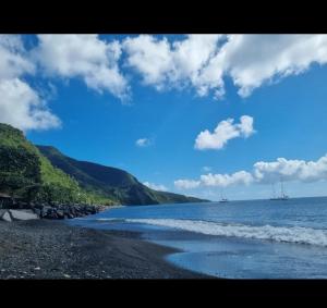 a view of a beach with a boat in the water at Petite Kaz KRÉOL in Basse-Terre