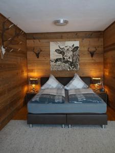 a bedroom with a bed with two lamps and a picture of a cow at Wohlfühlstudio Bergblick in Walchsee in Walchsee