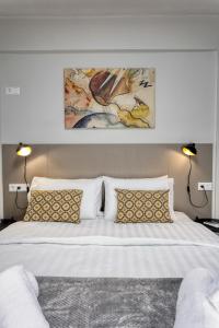 une chambre avec un grand lit blanc avec deux lampes dans l'établissement V P Trikala Luxury Suites, à Tríkala