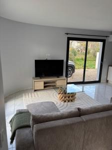 a living room with a couch and a flat screen tv at Maison neuve 2 chambres entre Dordogne et Corrèze in Terrasson-Lavilledieu