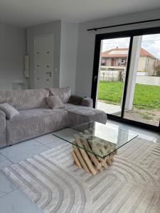 a living room with a couch and a glass table at Maison neuve 2 chambres entre Dordogne et Corrèze in Terrasson-Lavilledieu