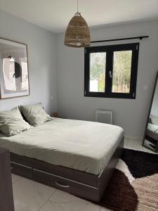 a bedroom with a bed with a mirror and a window at Maison neuve 2 chambres entre Dordogne et Corrèze in Terrasson-Lavilledieu