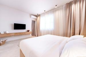 ein weißes Schlafzimmer mit einem Bett und einem Fernseher in der Unterkunft Vila VitaMaris in Okrug Donji
