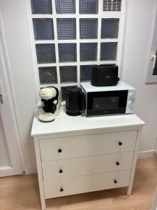uma cómoda branca com um micro-ondas em cima em Studio Cozy avec terrasse idéalement situé em Angers