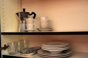 a shelf with plates and cups and a coffee maker at Charming studio by Lake Lucerne in Buochs +4 photos