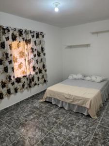a bedroom with a bed and a painting on the wall at Casa Gonzalez Oliveira in Mongaguá