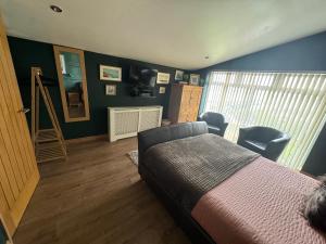 a bedroom with a bed and chairs and a window at Lakeland Guest House in Pembroke Dock