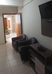 a living room with two chairs and a flat screen tv at Praticita Apart Hotel Ltda in São Gabriel