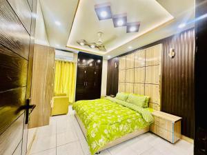 1 dormitorio con cama verde y techo en Grand apartments, en Lahore