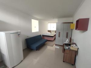 a living room with a blue couch and a bed at Studio Cyar 32 - Conforto e Praticidade in Taubaté