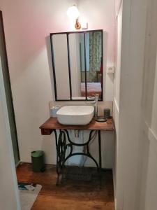 a bathroom with a sink and a mirror on a table at Grande maison de ville avec jardin Valence en Poitou pour 8 à 14 personnes in Couhé-Verac