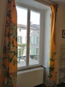 a window with an orange curtain in a room at Grande maison de ville avec jardin Valence en Poitou pour 8 à 14 personnes in Couhé-Verac