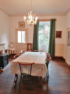 a dining room with a table and chairs and a chandelier at Grande maison de ville avec jardin Valence en Poitou pour 8 à 14 personnes in Couhé-Verac