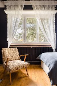 ein Schlafzimmer mit einem Stuhl, einem Bett und einem Fenster in der Unterkunft La Rose in Schiltigheim