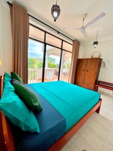 Schlafzimmer mit einem blauen Bett und einem großen Fenster in der Unterkunft French Residence Tangalle in Tangalle