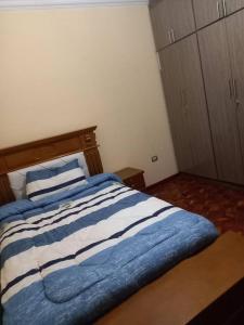 Una cama con sábanas de rayas azules y blancas en una habitación. en Guest house, en Addis Ababa