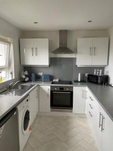 a kitchen with white cabinets and a dishwasher at Spacious two bedroom flat, entire property in Greenock