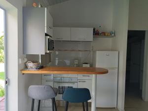 a kitchen with white cabinets and blue stools at Lantana in Sainte-Anne +8 photos